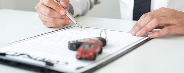 Car dealer businessman signing car insurance document or lease paper. Car loan and insurance concept.